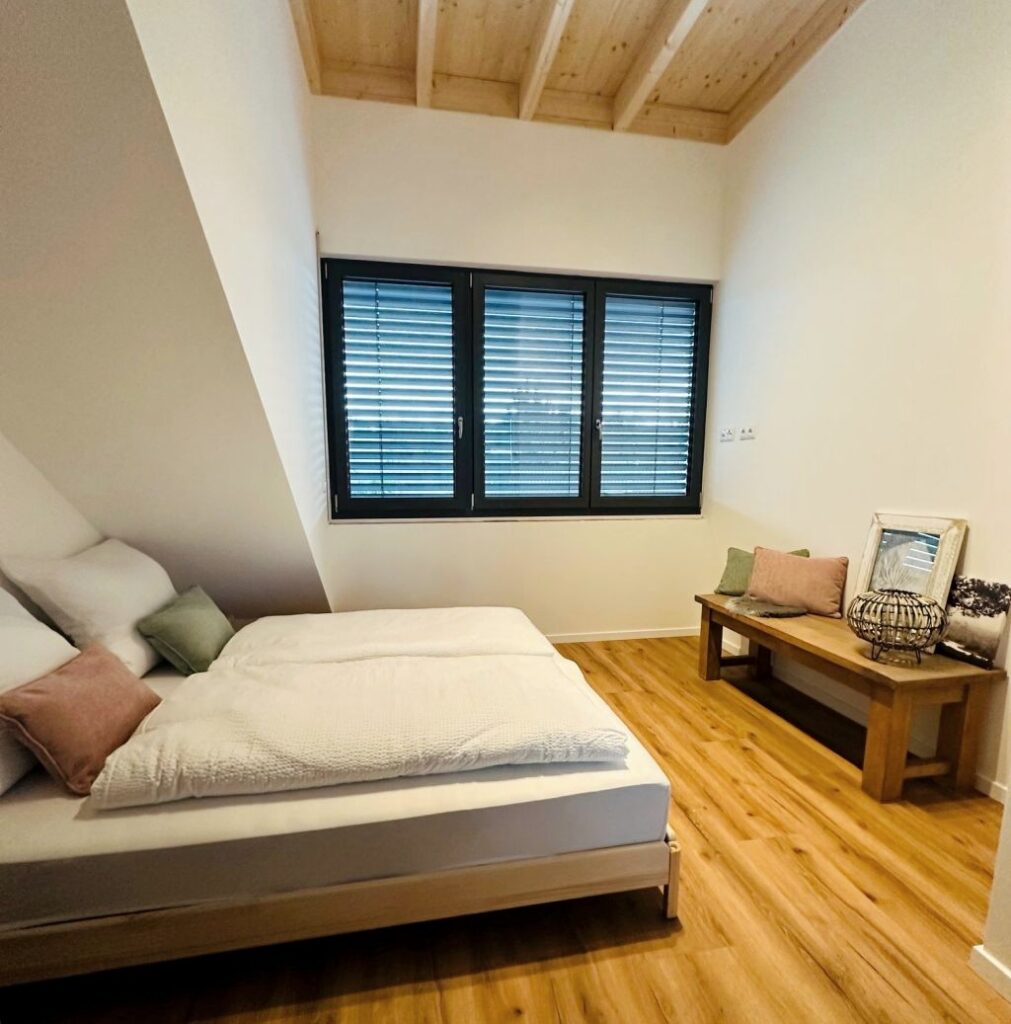 Schlafbereich im Appartement L mit Doppelbett und Fensterläden