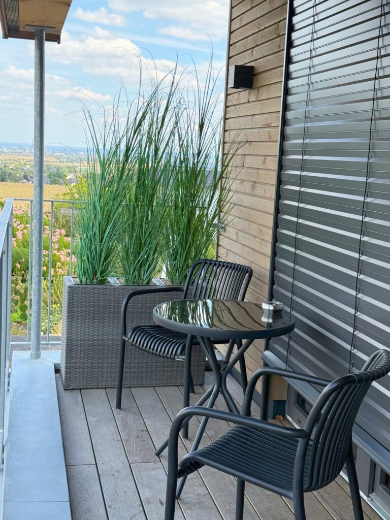 Balkon des Appartements M mit Tisch, Stühlen und Pflanzkübel