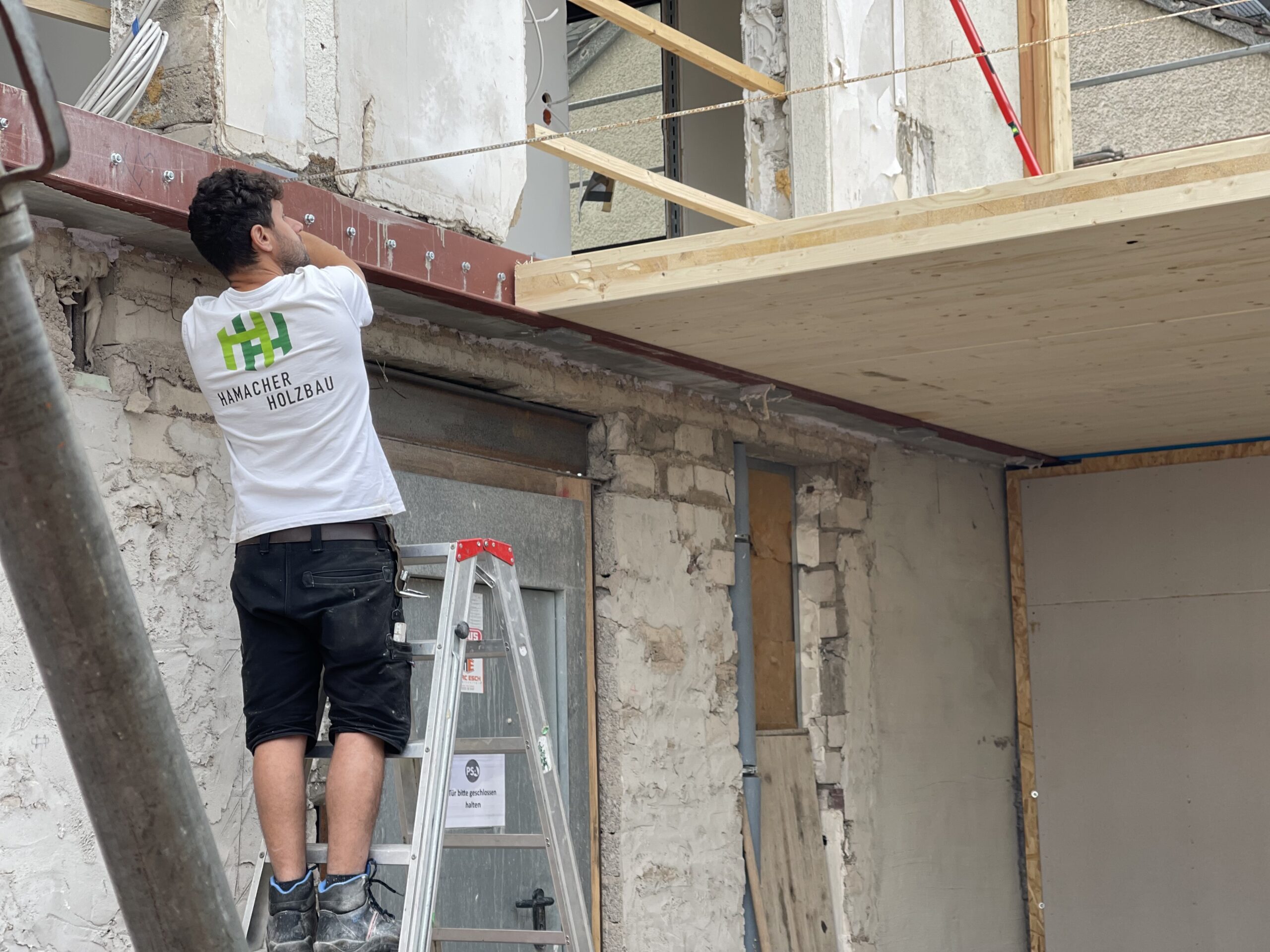 Zimmerer von Hamacher Holzbau montiert die Holzdecke des Anbaus über dem alten Mauerwerk