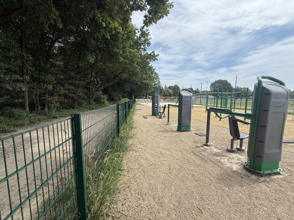 Outdoor-Fitnessgeräte am Sportplatz in Bornheim-Merten, daneben Bäume und Zaun